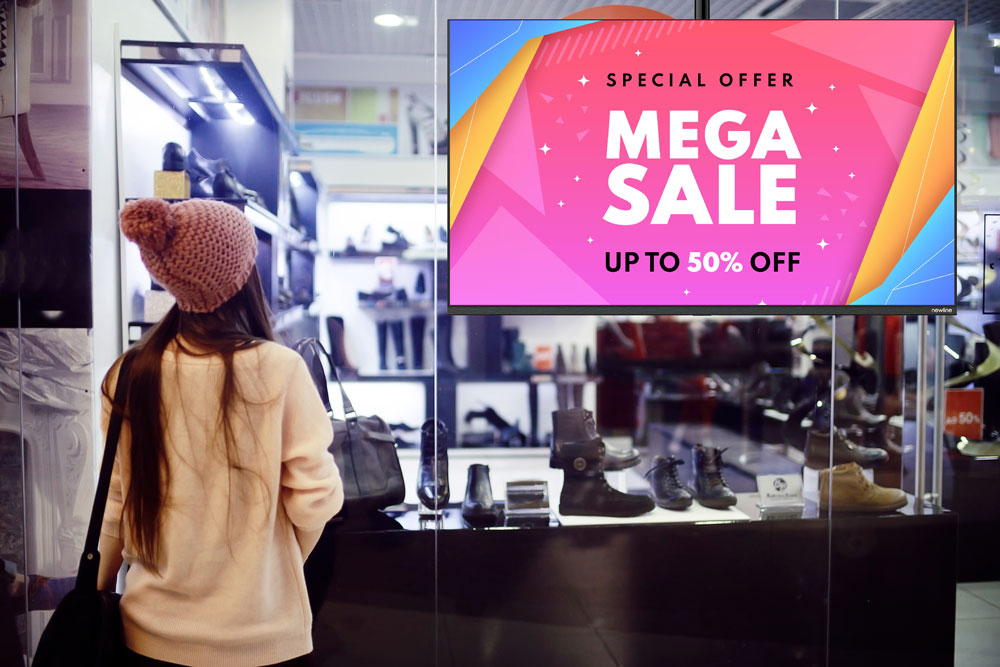 Digitalni oglasni ekran u trgovini odjee prikazuje popust na odjevne artikle.