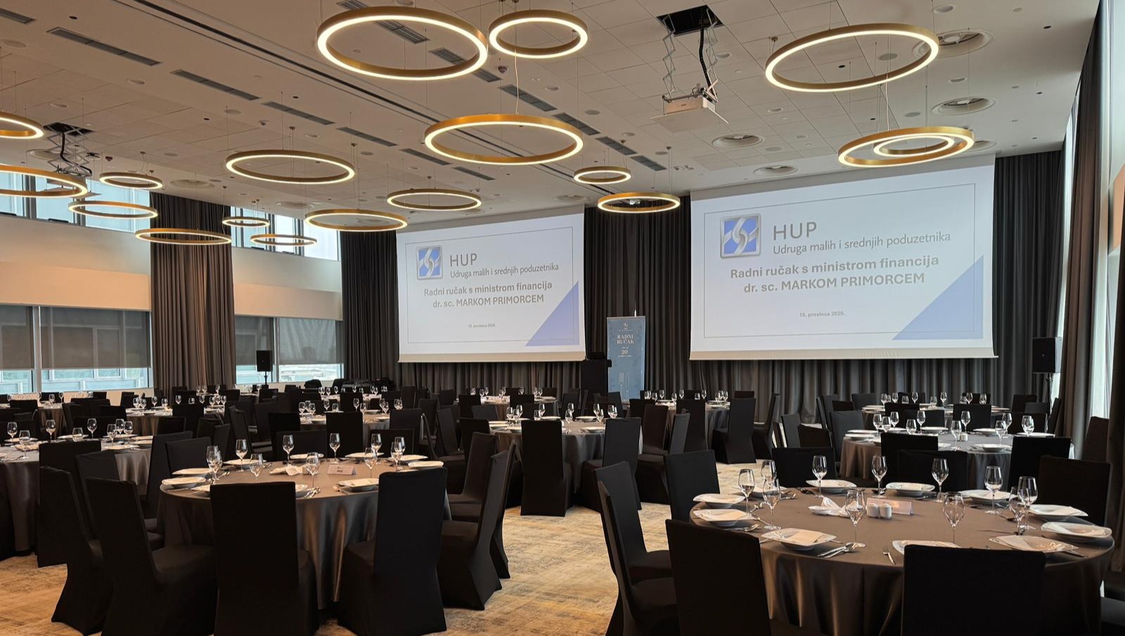 konferencijska dvorana s dva stropno montirana projektora i dva velika projekcijska platna pripremljena za poslovnu prezentaciju