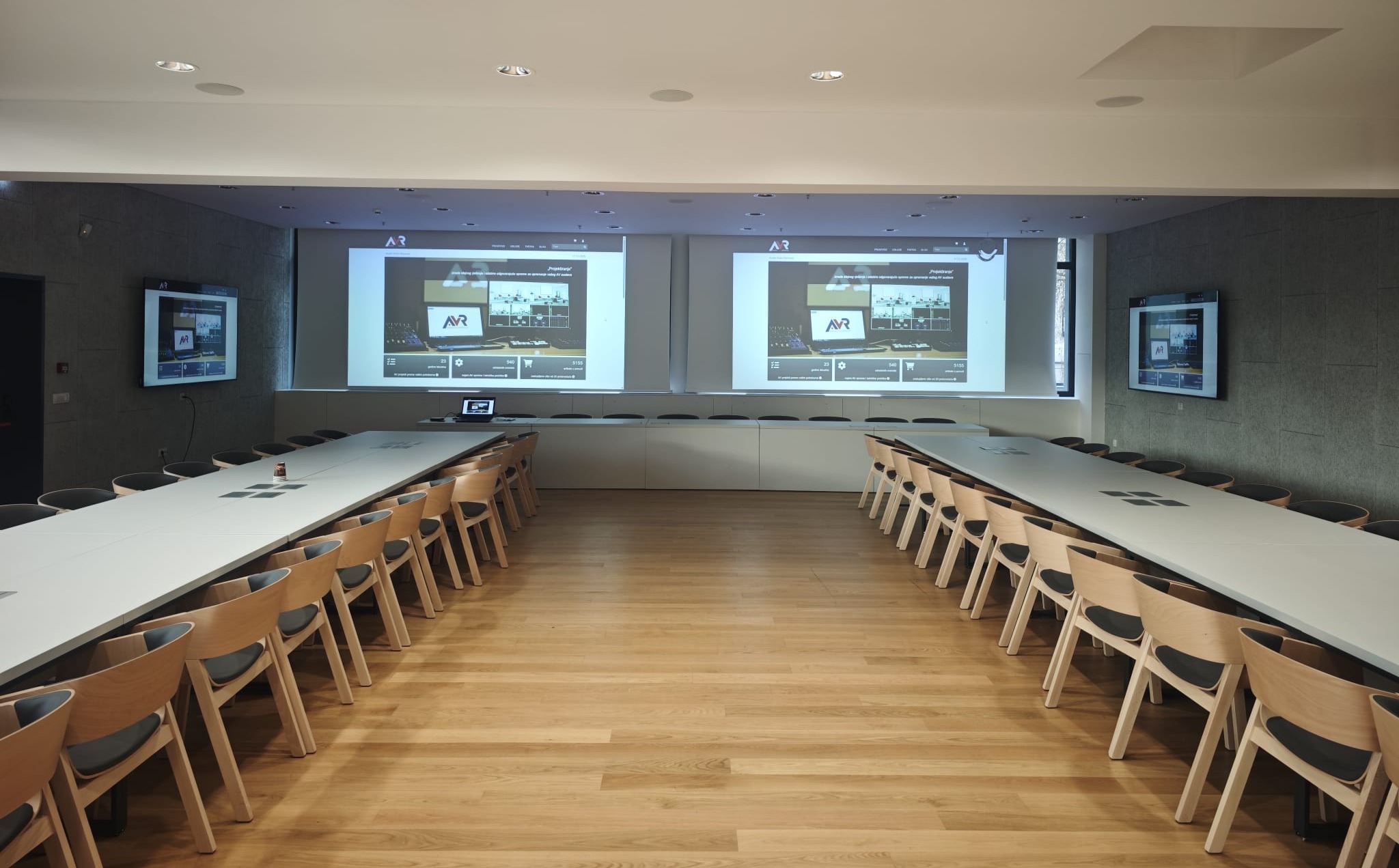 konferencijska dvorana s dva projekcijska platna i projekcijom pripremljena za poslovne prezentacije