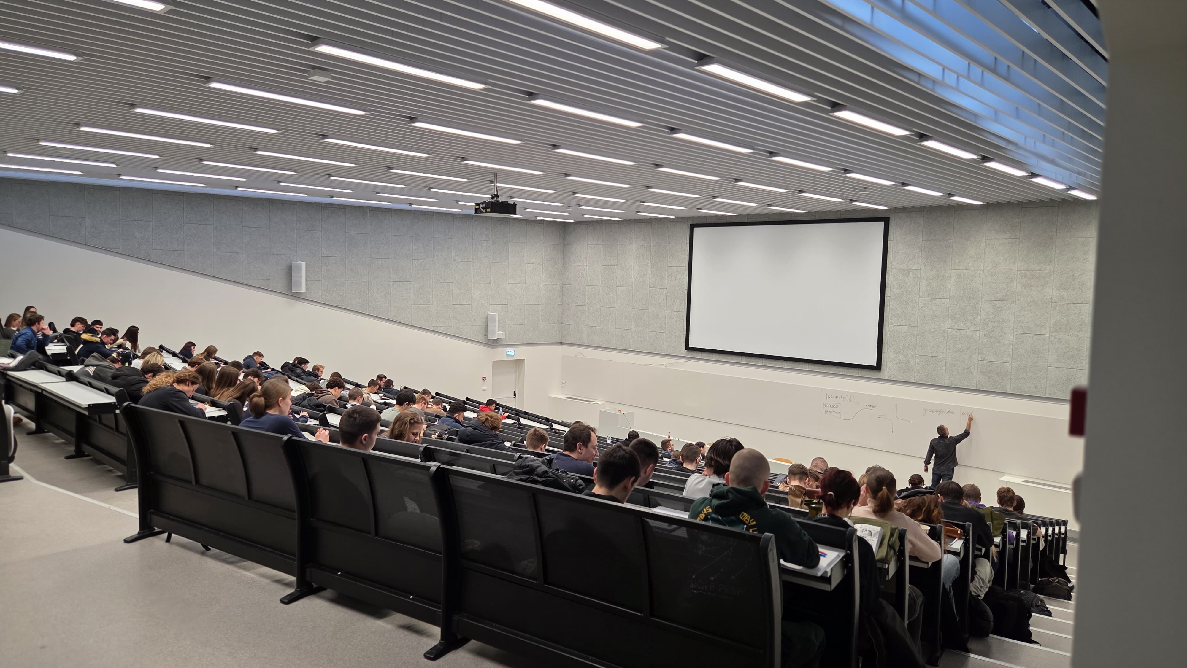 projektor za predavaonicu i veliko projekcijsko platno u punoj fakultetskoj predavaonici tijekom predavanja